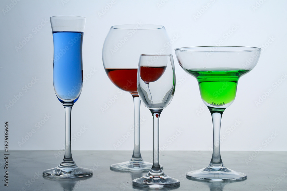 Four clear crystal glasses of different shape located at the empty background. Beautiful cocktail set at the bar. Four clear crystal glasses of different shape located at the empty background. Beautiful cocktail set at the bar.