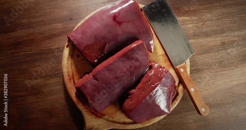 On the cutting board raw liver with a knife. 