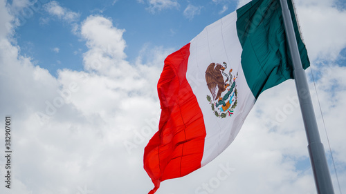 Mexican Flag Waving in the Wind and Cloudy Sky as the Background photo