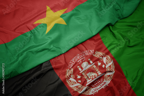 waving colorful flag of afghanistan and national flag of burkina faso. macro