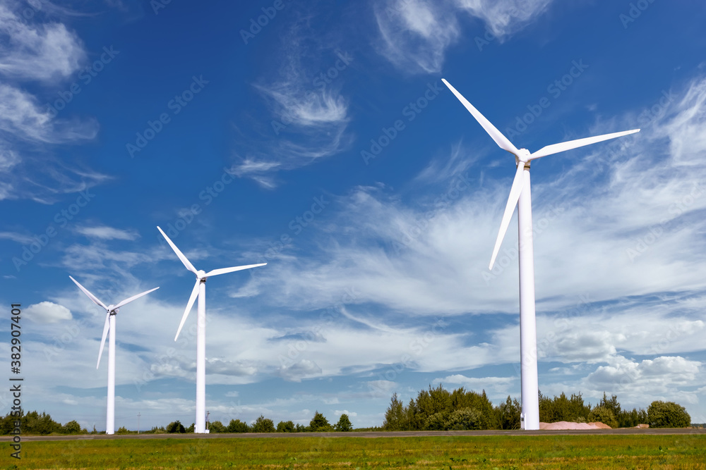 A group of windmills for generating renewable electricity against a sky background with beautiful clouds A group of windmills for generating renewable electricity against a sky background with beautiful clouds