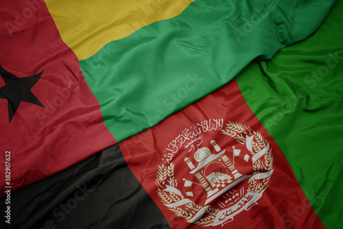 waving colorful flag of afghanistan and national flag of guinea bissau. macro