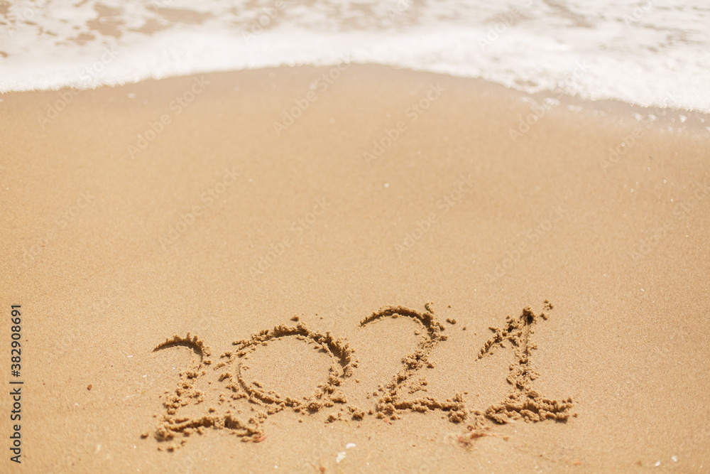Hello 2021! Happy new year 2021 sign handwritten on sandy beach with waves and white foam Hello 2021! Happy new year 2021 sign handwritten on sandy beach with waves and white foam