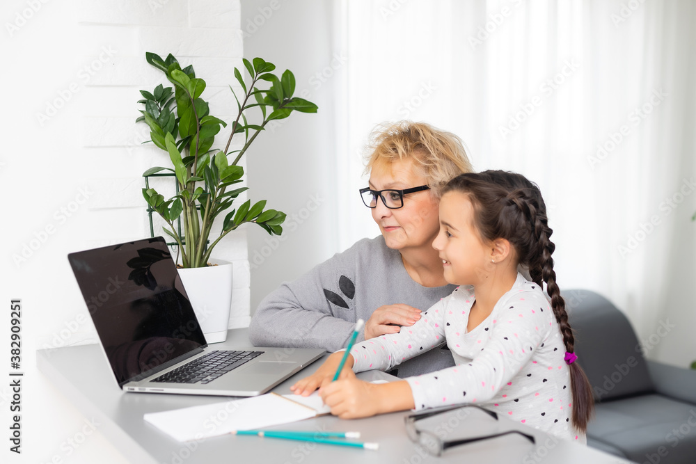 Helpful granny. Helpful loving granny assisting her cute granddaughter making homework Helpful granny. Helpful loving granny assisting her cute granddaughter making homework
