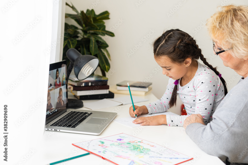 Cute and happy little girl child using laptop computer with her grandma, studying through online e-learning system. Cute and happy little girl child using laptop computer with her grandma, studying through online e-learning system.