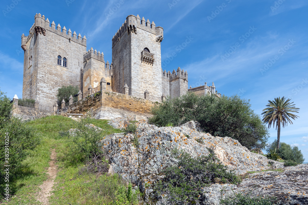 mposing medieval castle of Almodovar del Rio on a hill and a beautiful blue sky and white clouds
