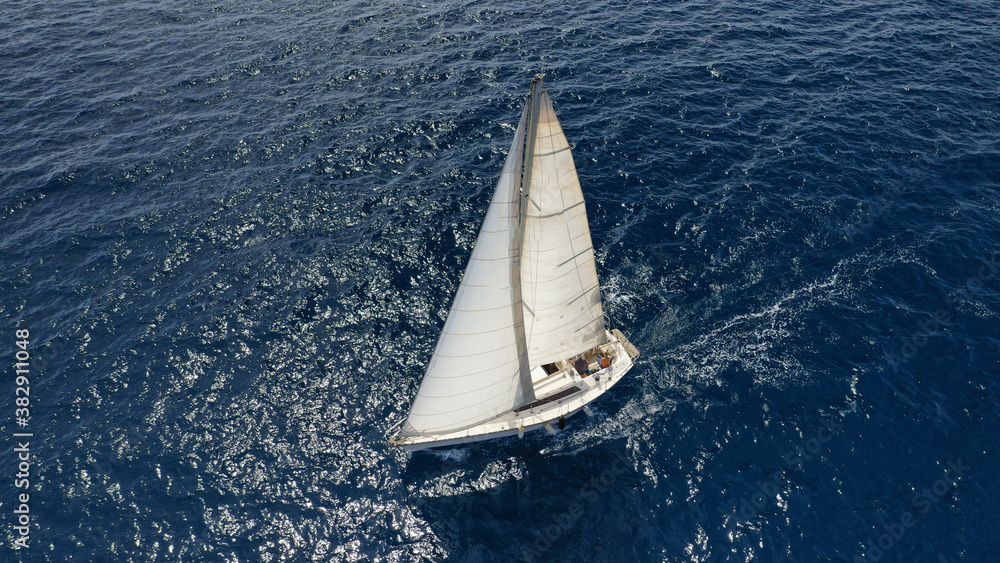 Aerial drone photo of sailboat cruising in Mediterranean deep blue open ocean sea