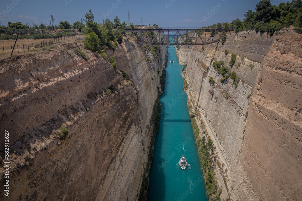 Corinth or corinthian canal in Greece. A narrow waterway that connects Ionic sea with Aegean sea. Narrow water passage carved in rock on a sunny day.