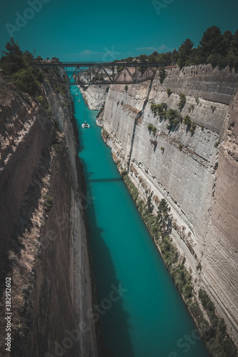 Corinth or corinthian canal in Greece. A narrow waterway that connects Ionic sea with Aegean sea. Narrow water passage carved in rock on a sunny day.