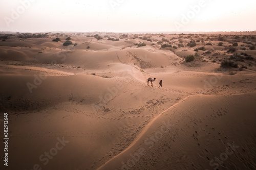 Aerial View Of Person Walking A Camel Across Great Indian Desert At Sunset photo