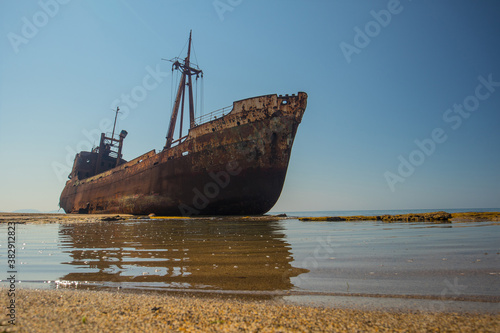 Dimitrios shipwreck in  Gythio, Greece. A partially sunken rusty and metal shipwreck decaying through time on a sandy beach on a sunny day. Famous shipwreck in greece. © Anze
