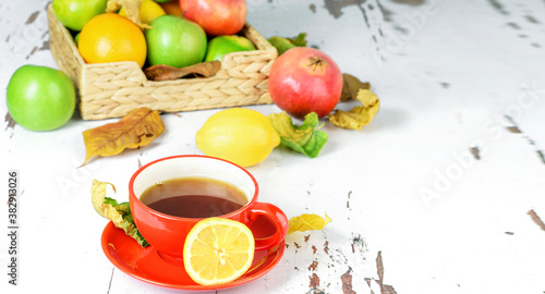 A cup of hot tea with limon, fresh oragnic fruits as booster of immunity, antivirus remedy.