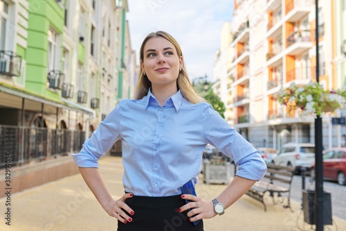 Outdoor portrait of young confident business woman with folded hands