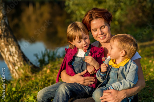 happy family Mom and children sit on the river bank