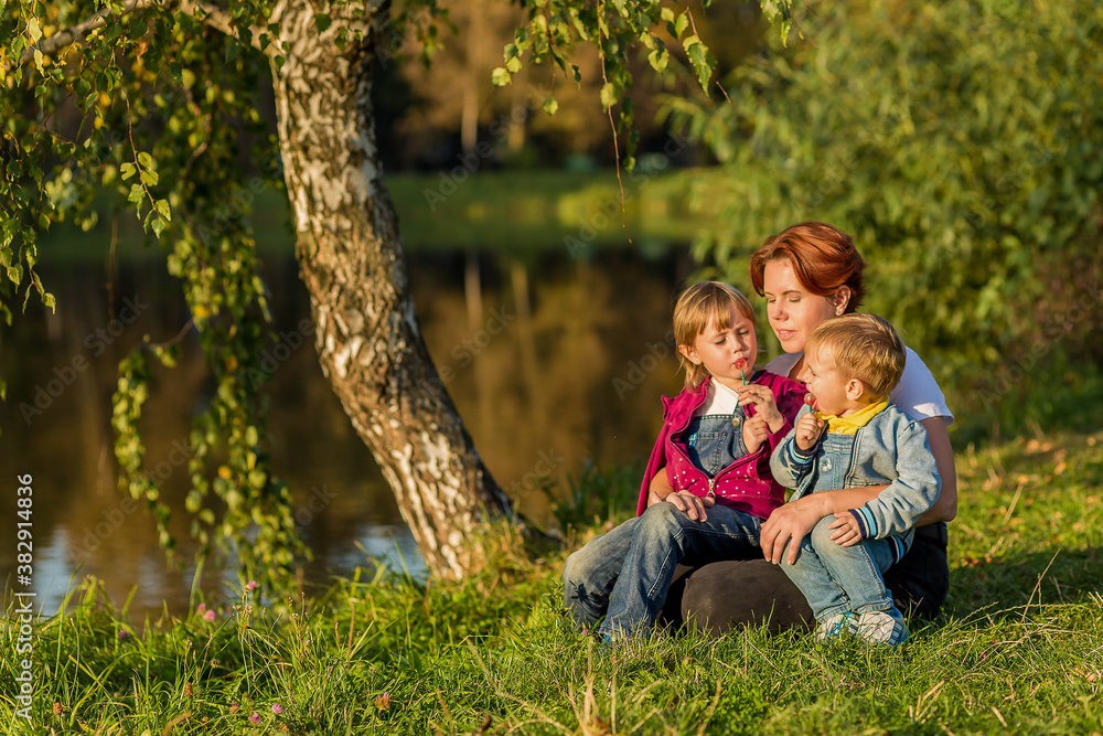 happy family Mom and children sit on the river bank happy family Mom and children sit on the river bank