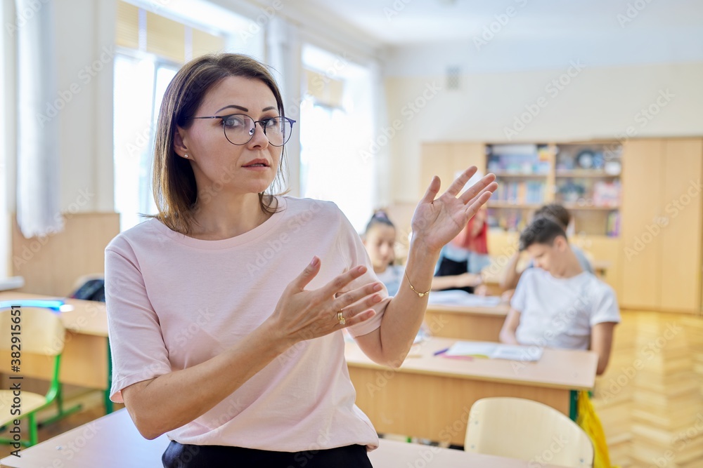 Fototapeta premium Mature woman teacher talking makes presentation teaches looking at camera