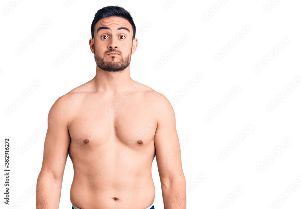Young handsome man wearing swimwear puffing cheeks with funny face. mouth inflated with air, crazy expression. Young handsome man wearing swimwear puffing cheeks with funny face. mouth inflated with air, crazy expression.
