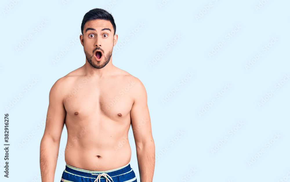 Fototapeta premium Young handsome man wearing swimwear afraid and shocked with surprise and amazed expression, fear and excited face.
