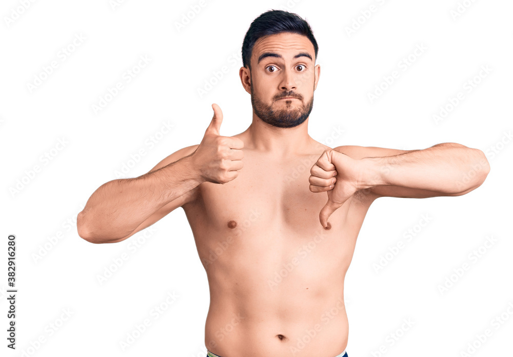 Fototapeta premium Young handsome man wearing swimwear doing thumbs up and down, disagreement and agreement expression. crazy conflict