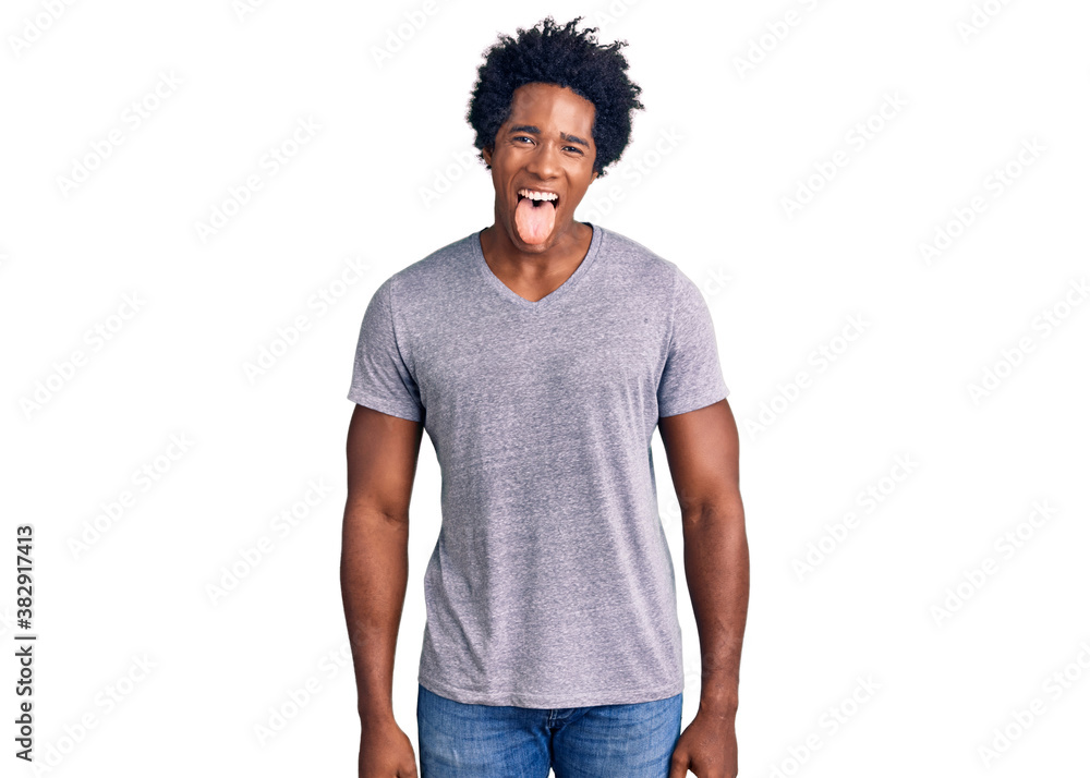 Handsome african american man with afro hair wearing casual clothes sticking tongue out happy with funny expression. emotion concept. Handsome african american man with afro hair wearing casual clothes sticking tongue out happy with funny expression. emotion concept.