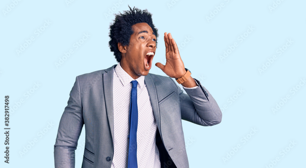 Handsome african american man with afro hair wearing business jacket shouting and screaming loud to side with hand on mouth. communication concept. Handsome african american man with afro hair wearing business jacket shouting and screaming loud to side with hand on mouth. communication concept.