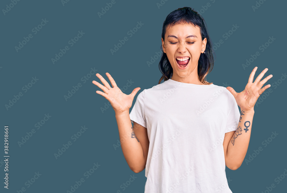 Young woman wearing casual clothes celebrating mad and crazy for success with arms raised and closed eyes screaming excited. winner concept Young woman wearing casual clothes celebrating mad and crazy for success with arms raised and closed eyes screaming excited. winner concept