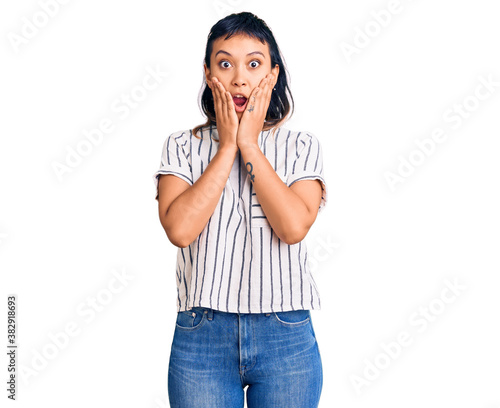 Young woman wearing casual clothes afraid and shocked, surprise and amazed expression with hands on face