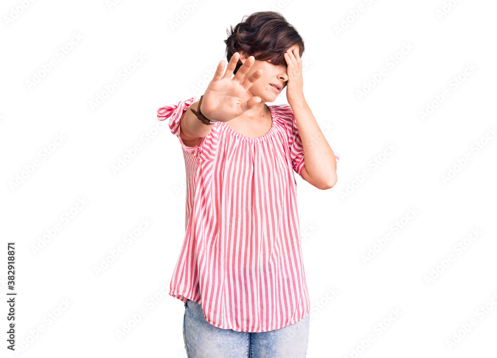 Beautiful young woman with short hair wearing casual summer clothes covering eyes with hands and doing stop gesture with sad and fear expression. embarrassed and negative concept. Beautiful young woman with short hair wearing casual summer clothes covering eyes with hands and doing stop gesture with sad and fear expression. embarrassed and negative concept.