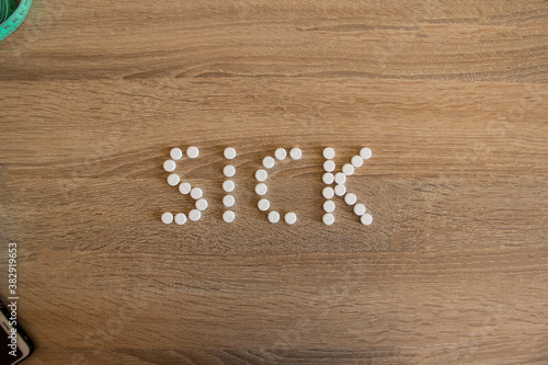 The word sick is laid out on a wooden table.