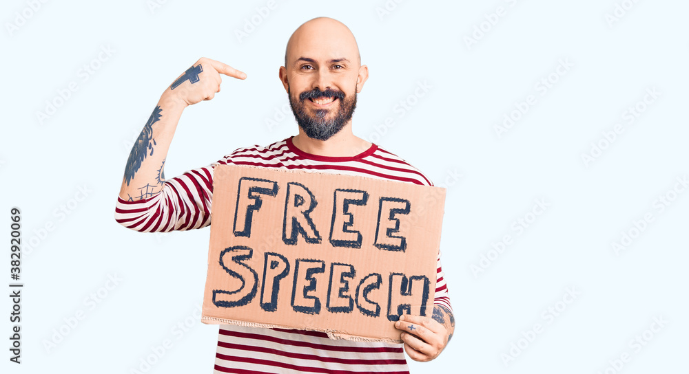 Young handsome man holding free speech banner pointing finger to one self smiling happy and proud Young handsome man holding free speech banner pointing finger to one self smiling happy and proud