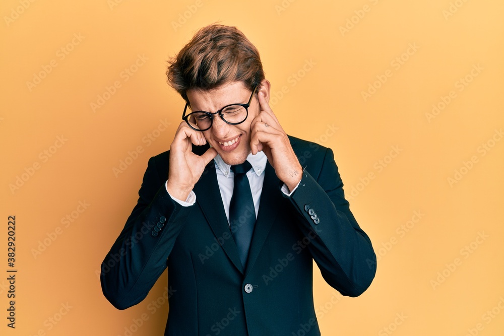 Handsome caucasian man wearing business suit and tie covering ears with fingers with annoyed expression for the noise of loud music. deaf concept. Handsome caucasian man wearing business suit and tie covering ears with fingers with annoyed expression for the noise of loud music. deaf concept.