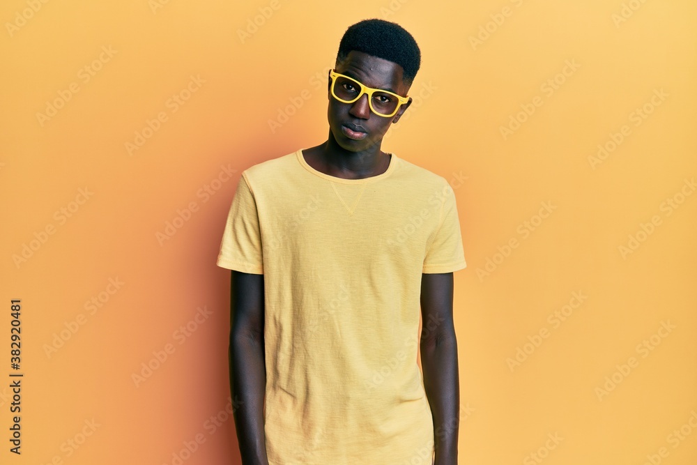 Young african american man wearing casual clothes and glasses skeptic and nervous, frowning upset because of problem. negative person. Young african american man wearing casual clothes and glasses skeptic and nervous, frowning upset because of problem. negative person.