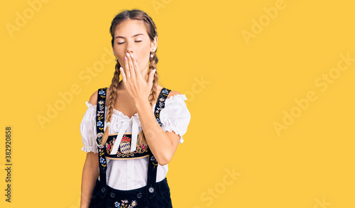 Beautiful caucasian woman with blonde hair wearing octoberfest traditional clothes bored yawning tired covering mouth with hand. restless and sleepiness.