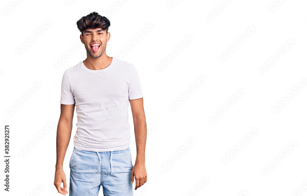 Young hispanic man wearing casual clothes sticking tongue out happy with funny expression. emotion concept. Young hispanic man wearing casual clothes sticking tongue out happy with funny expression. emotion concept.