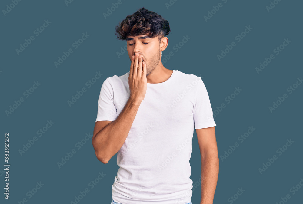 Young hispanic man wearing casual clothes bored yawning tired covering mouth with hand. restless and sleepiness. Young hispanic man wearing casual clothes bored yawning tired covering mouth with hand. restless and sleepiness.