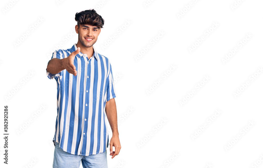 Young hispanic man wearing casual clothes smiling friendly offering handshake as greeting and welcoming. successful business. Young hispanic man wearing casual clothes smiling friendly offering handshake as greeting and welcoming. successful business.