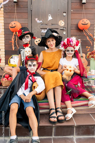 Young happy woman and group of cute halloween kids in smart costumes
