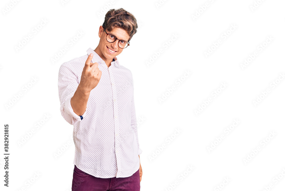 Young handsome man wearing business clothes and glasses beckoning come here gesture with hand inviting welcoming happy and smiling Young handsome man wearing business clothes and glasses beckoning come here gesture with hand inviting welcoming happy and smiling