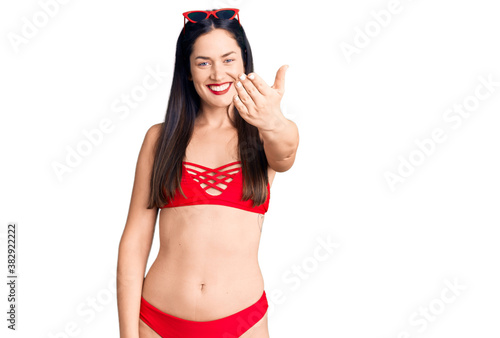 Young beautiful caucasian woman wearing bikini smiling friendly offering handshake as greeting and welcoming. successful business. photo