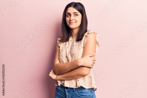 Young beautiful girl wearing casual clothes smiling happy and confident. Standing with smile on face and arms crossed over isolated pink background
