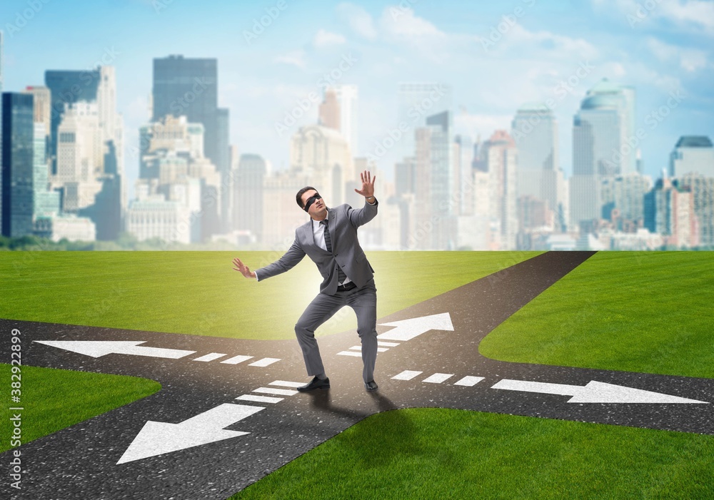 Young businessman at crossroads in uncertainty concept Young businessman at crossroads in uncertainty concept