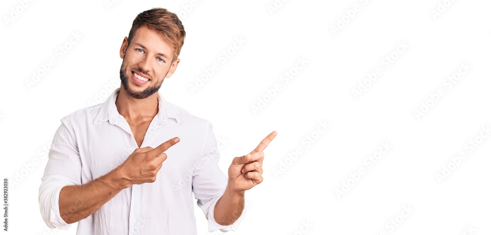Young caucasian man wearing casual clothes smiling and looking at the camera pointing with two hands and fingers to the side. Young caucasian man wearing casual clothes smiling and looking at the camera pointing with two hands and fingers to the side.
