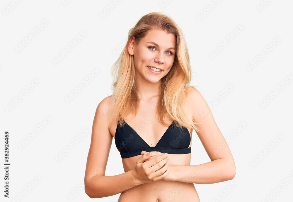 Young beautiful blonde woman wearing bikini with hands together and crossed fingers smiling relaxed and cheerful. success and optimistic Young beautiful blonde woman wearing bikini with hands together and crossed fingers smiling relaxed and cheerful. success and optimistic