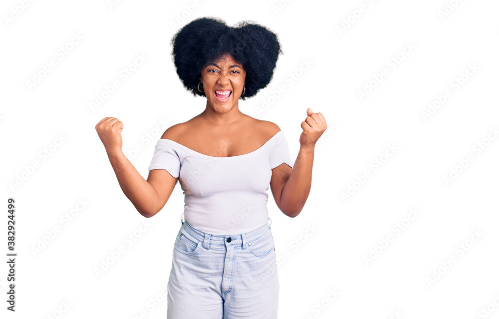 Young african american girl wearing casual clothes screaming proud, celebrating victory and success very excited with raised arms Young african american girl wearing casual clothes screaming proud, celebrating victory and success very excited with raised arms