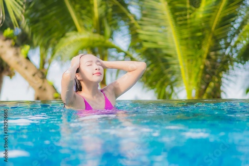 Portrait beautiful young asian woman smile relax around outdoor swimming pool in resort