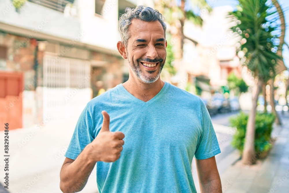 Middle age grey-haired man wearing casual clothes at street of city smiling happy and positive, thumb up doing excellent and approval sign Middle age grey-haired man wearing casual clothes at street of city smiling happy and positive, thumb up doing excellent and approval sign