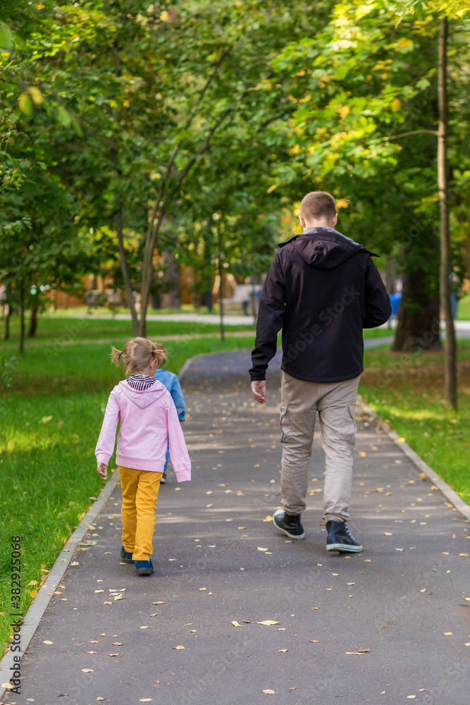 Fototapeta premium .Dad with children walking along the path in the park on an autumn walk.