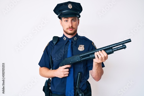 Young caucasian man wearing police uniform holding shotgun skeptic and nervous, frowning upset because of problem. negative person. photo