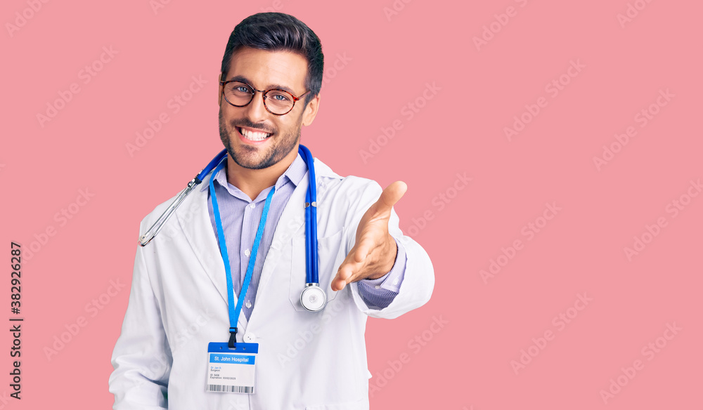 Young hispanic man wearing doctor uniform and stethoscope smiling cheerful offering palm hand giving assistance and acceptance. Young hispanic man wearing doctor uniform and stethoscope smiling cheerful offering palm hand giving assistance and acceptance.