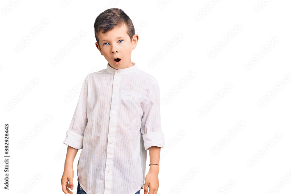 Cute blond kid wearing elegant shirt in shock face, looking skeptical and sarcastic, surprised with open mouth Cute blond kid wearing elegant shirt in shock face, looking skeptical and sarcastic, surprised with open mouth